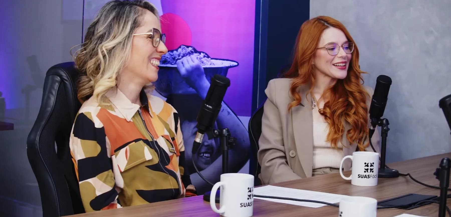 Duas apresentadoras do SUASCAST em frente aos microfones, no estúdio de gravação